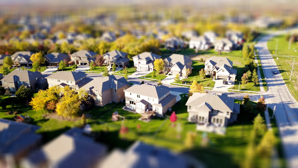 Professional real estate agent stands outside a suburban home, having a supportive and serious conversation with the homeo...