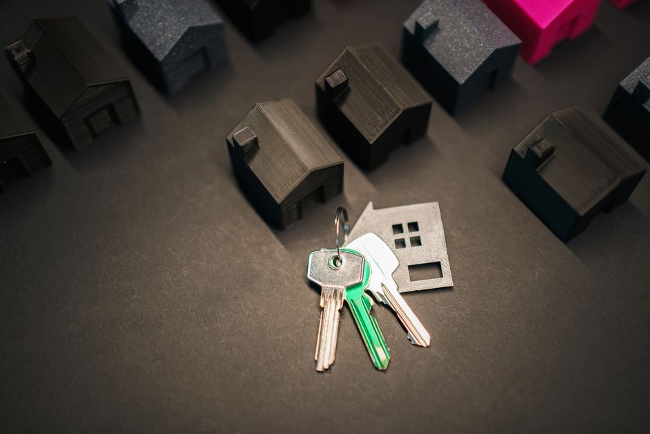 A clean, minimalist flat lay showing a real estate law book, a set of house keys, and a pen on a bright surface, symbolizing the essential knowledge learned to become an agent.