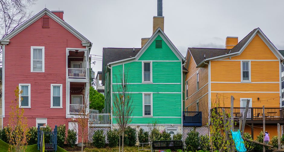 A bright, sunny shot of a street with a row of identical modern suburban homes, illustrating the uniformity enforced by a Homeowner's Association.