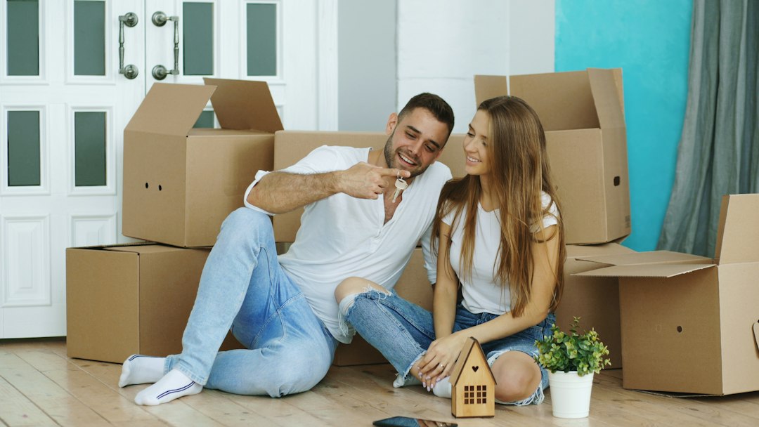 A hopeful family smiling while carrying moving boxes into their new, modern suburban home, symbolizing a fresh start and relocation.